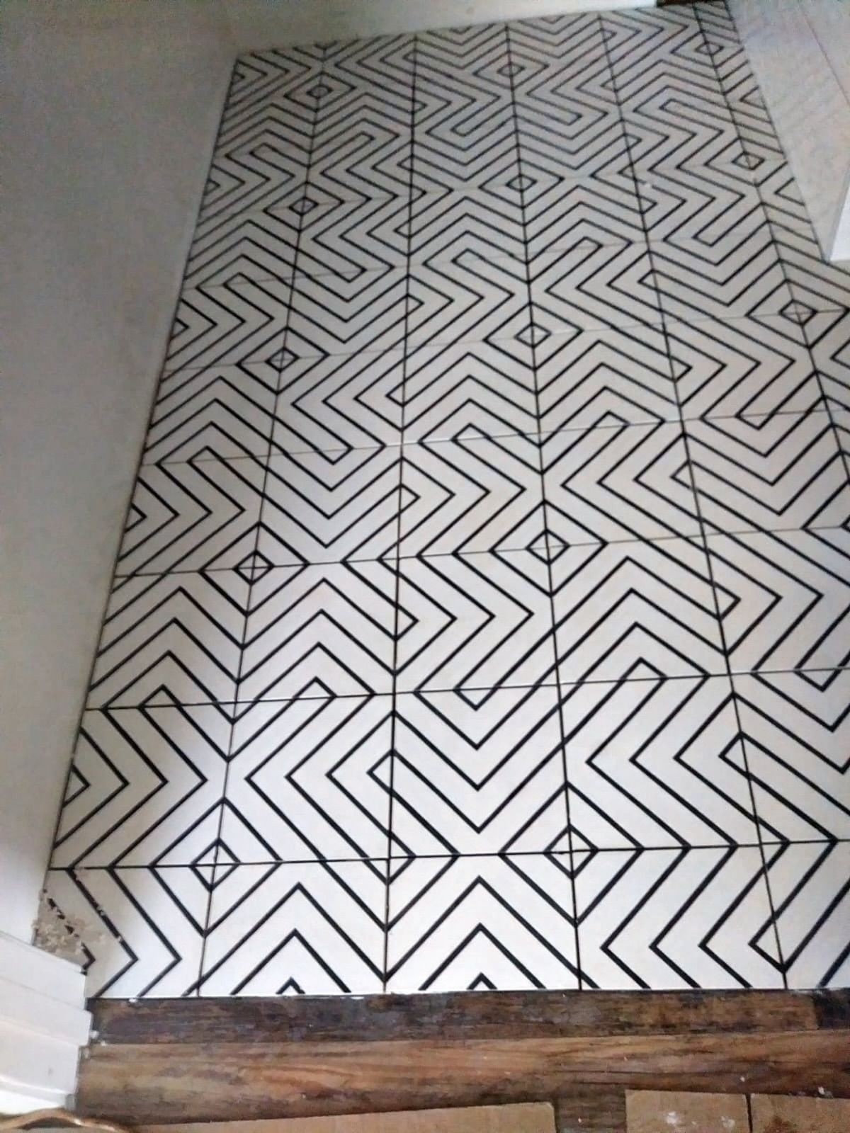 Geometric black and white patterned floor tiles with a zigzag and diamond design seen from above.